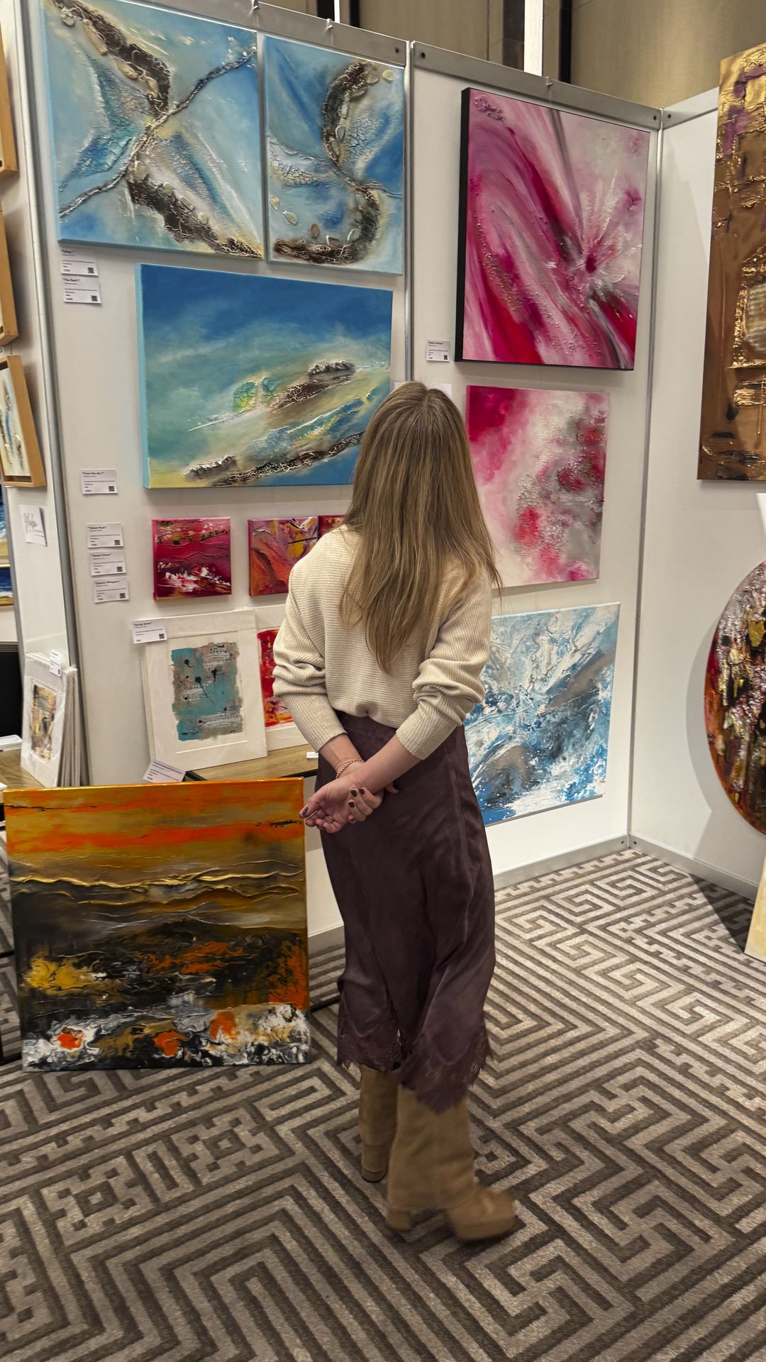 Visitor observing textured abstract paintings in blue and pink tones at ART.CY 2026