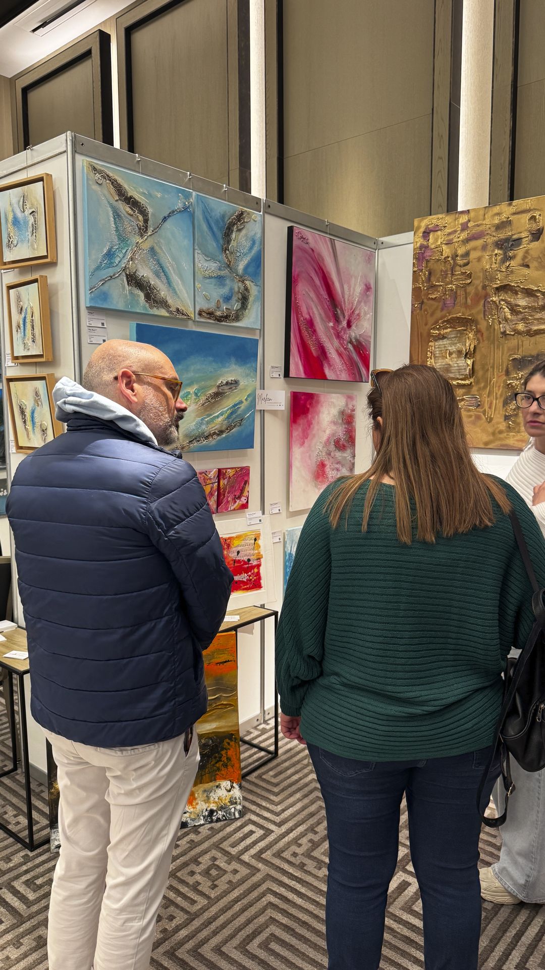 Visitors engaging with abstract mixed media artworks at ART.CY 2026 Limassol